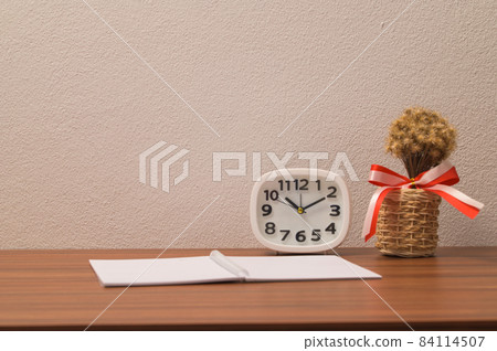 The notebook and the clock are on the table. The notebook and the clock are on the table. 84114507