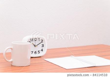 The notebook and the clock are on the table. The notebook and the clock are on the table. 84114510