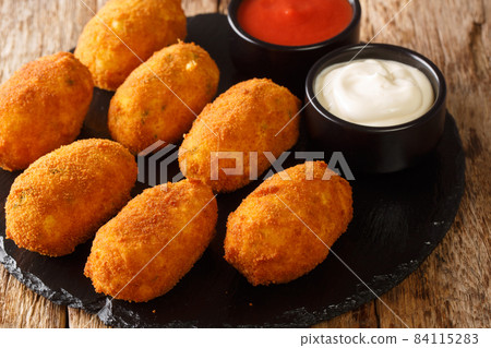 Spanish croquettes with salted cod served with sauces close-up on a slate plate. horizontal Spanish croquettes with salted cod served with sauces close-up on a slate plate. horizontal 84115283