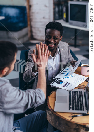 Business partners giving high five at table. Business partners giving high five at table. 84117367