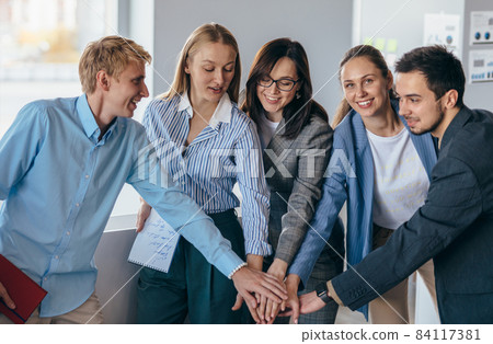 Business team showing unity with their hands together Business team showing unity with their hands together 84117381