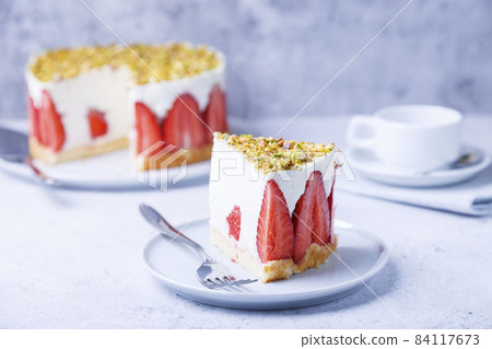 Freesier cake with fresh strawberries and pistachios. French classic dessert. Portion of cake on a white plate close-up. Freesier cake with fresh strawberries and pistachios. French classic dessert. Portion of cake on a white plate close-up. 84117673