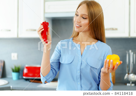 Blonde woman standing in kitchen and cooking Blonde woman standing in kitchen and cooking 84118418