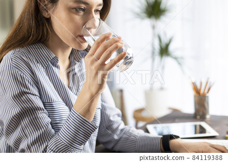 Freelancer young woman working at home and drinking water Freelancer young woman working at home and drinking water 84119388