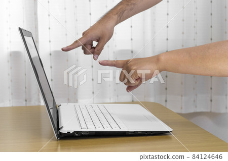 Men's and women's hands pointing at the screen of a laptop computer (Japanese, 30s) 84124646
