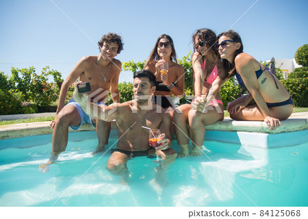 Contented friends taking selfie at poolside 84125068