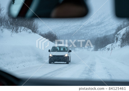 Van driving on highway road with snow covered in blizzard 84125461