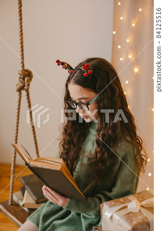happy teenage girl sitting near christmas tree 84125516