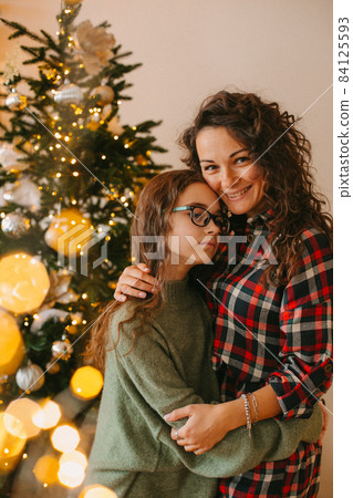 Happy young woman with cute teenage daughter in christmas interior Happy young woman with cute teenage daughter in christmas interior 84125593