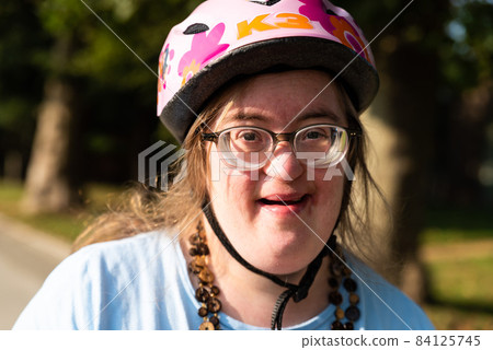 Outdoor portrait of a 39 year old cheerful woman with down syndrome on her bike Outdoor portrait of a 39 year old cheerful woman with down syndrome on her bike 84125745