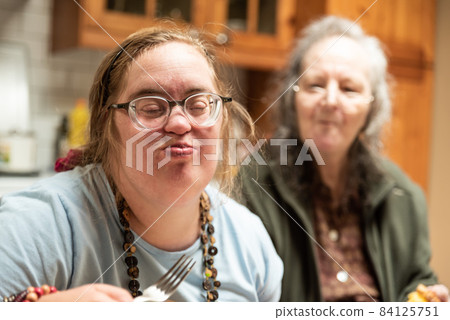 Hakendover, Flemish Brabant, Belgium - 09 20 2021: Disabled 39 year old woman and her 83 year old mother having fun in the kitchen at home Hakendover, Flemish Brabant, Belgium - 09 20 2021: Disabled 39 year old woman and her 83 year old mother having fun in the kitchen at home 84125751