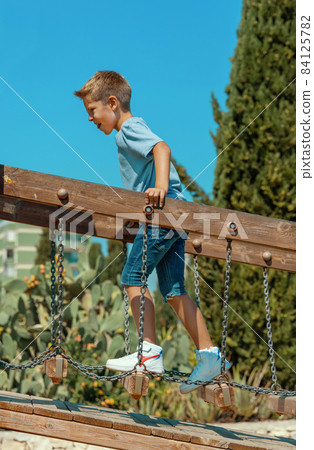 Kid boy playing on playground in park in a warm sunny day 84125782