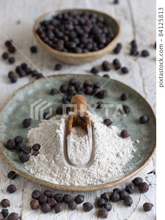 Plate and wooden scoop of black chickpea flour and beans closeup 84125813