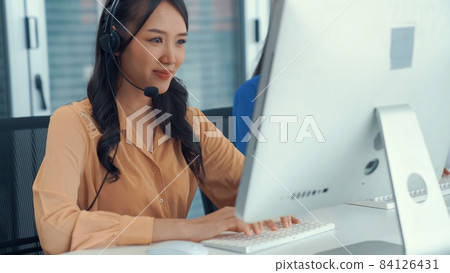 Businesswoman wearing headset working actively in office Businesswoman wearing headset working actively in office 84126431