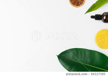 Essential oil in a small bottle with green leaf on white background 84127395