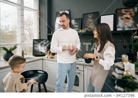 Happy young family spending time together in kitchen at home at Christmas 84127396