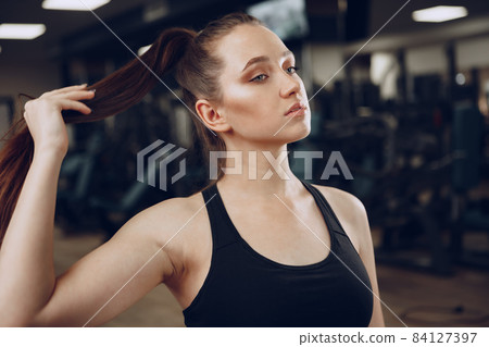 Brunette young woman sitting tired in a gym after workout 84127397