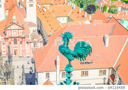 Bronze cock at spire of St. Vitus Cathedral with courtyard square of Prague Castle 84128489