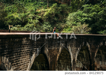 The girl on the edge of the bridge. Nine-arch bridge. Travelling to Asia. Travel to Sri Lanka. The man on the bridge. Sightseeing In Asia. Excursion to Sri Lanka. Colonial heritage The girl on the edge of the bridge. Nine-arch bridge. Travelling to Asia. Travel to Sri Lanka. The man on the bridge. Sightseeing In Asia. Excursion to Sri Lanka. Colonial heritage 84129073