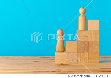 Stacked wooden blocks on wooden desk against blue background Stacked wooden blocks on wooden desk against blue background 84129081