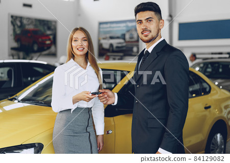Young attractive woman buying a new car in car salon Young attractive woman buying a new car in car salon 84129082