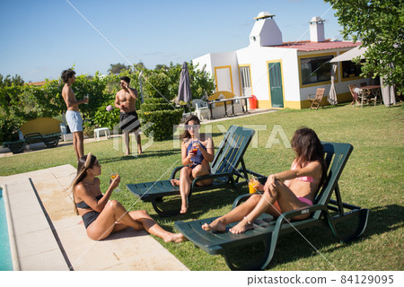 Content friends partying near swimming pool Content friends partying near swimming pool 84129095