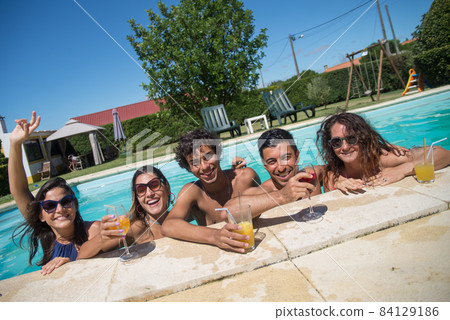 Smiling friends resting at poolside 84129186