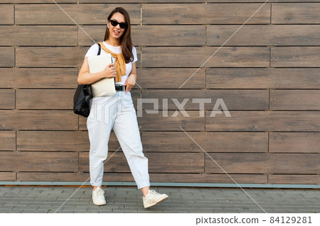 Photo of fascinating beautiful smiling charming young brunette girl wearing stylish clothes holding Photo of fascinating beautiful smiling charming young brunette girl wearing stylish clothes holding 84129281