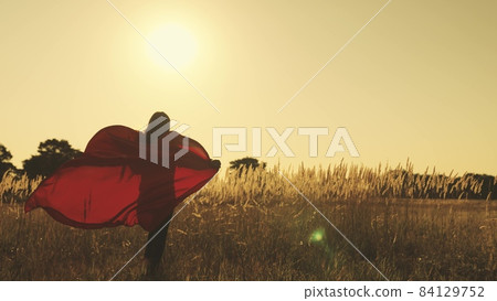 happy teenage girl in developing red cloak in wind at sunset in the sky, dreaming of becoming superhero protecting weak and not wine people, defeating evil, good person who does good loves to help 84129752
