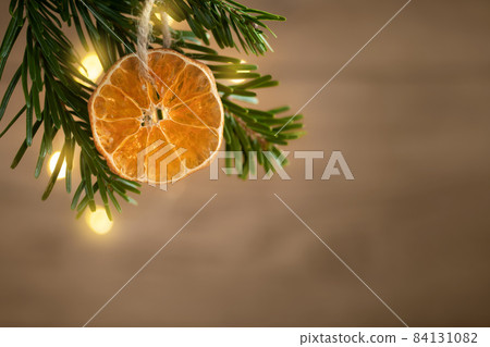 Zero waste and eco friendly christmas concept. Dried orange on a Christmas tree branch on a background of a wooden wall, copy space Zero waste and eco friendly christmas concept. Dried orange on a Christmas tree branch on a background of a wooden wall, copy space 84131082