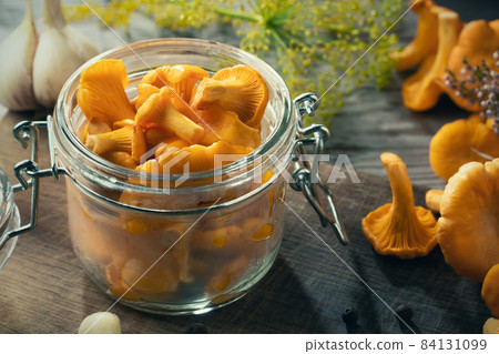 Preserving chanterelle mushrooms in a jar with spices and herbs. Pickling wild edible mushrooms, close-up 84131099