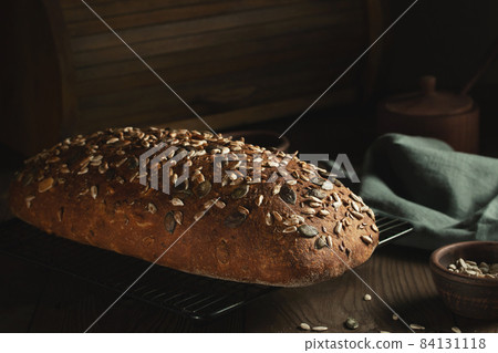 Loaf of homemade whole grain bread with seeds cool down on a wire rack on a wooden table Loaf of homemade whole grain bread with seeds cool down on a wire rack on a wooden table 84131118