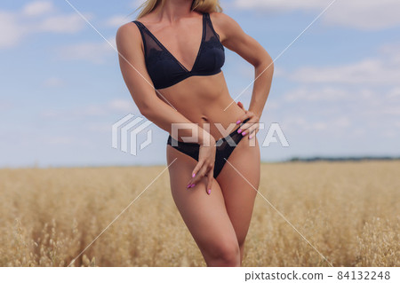 A young woman in underwear in a field of wheat. A young woman in underwear in a field of wheat. 84132248
