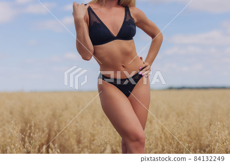 A young woman in underwear in a field of wheat. A young woman in underwear in a field of wheat. 84132249
