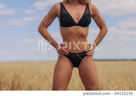 A young woman in underwear in a field of wheat. A young woman in underwear in a field of wheat. 84132250