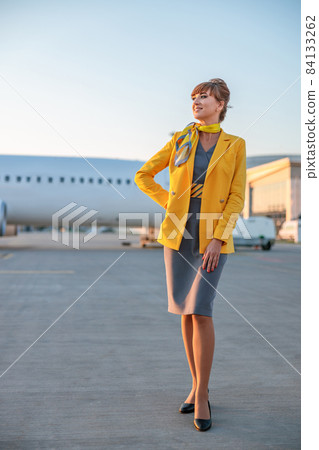 Joyful stewardess or air hostess standing outdoors at airport 84133262