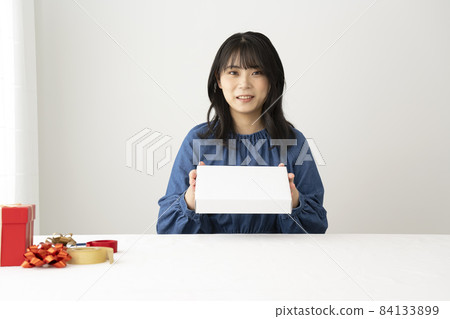 A woman assembling a box to put gifts at her desk 84133899