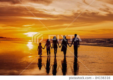 Silhouettes of big happy family holding the arms each other's on beach during golden sunset Silhouettes of big happy family holding the arms each other's on beach during golden sunset 84136316
