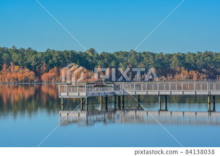 A reflection of the fishing pier and Fall leaf colors on Little Ocmulgee River in McRae, Georgia 84138038