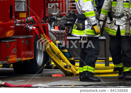消防過程中連接消防水帶的泵車和消防員 84138888