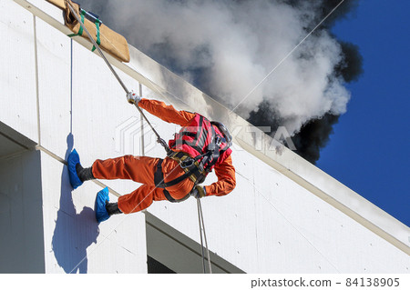 Fire drills by rescue workers climbing walls with ropes to carry out rescue operations 84138905