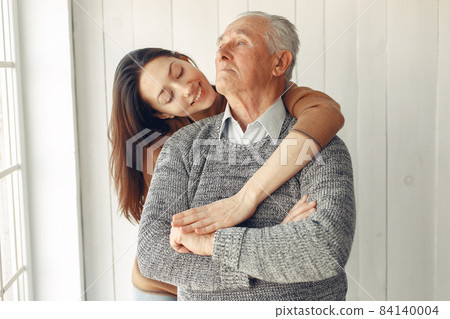 Elegant old man standing at home with his granddaughter 84140004