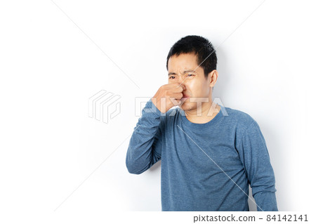 Portrait of young man pinching nose on his face due to bad smell isolated on white background Portrait of young man pinching nose on his face due to bad smell isolated on white background 84142141