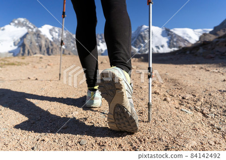 Traveler with trekking poles is walking in the mountains. 84142492