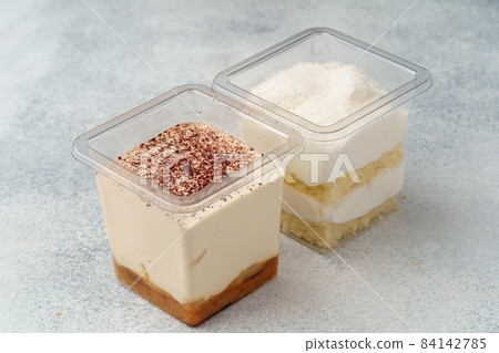 Creamy dessert in a plastic box on gray table Creamy dessert in a plastic box on gray table 84142785