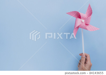 close up human hand holding polka dotted pinwheel blue backdrop. High quality beautiful photo concept 84143655