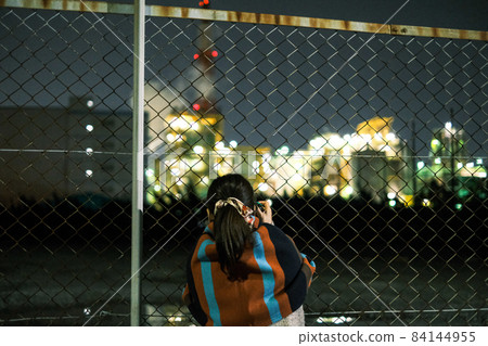A woman shooting a factory night view A woman shooting a factory night view 84144955