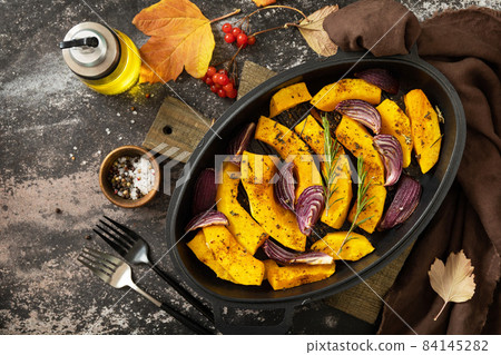Pumpkins slice with rosemary and purple onion, baking fresh healthy food with spice on a dark stone background. Keto or paleo diet veggie vegan or vegetarian. Top view flat lay background. Copy space. Pumpkins slice with rosemary and purple onion, baking fresh healthy food with spice on a dark stone background. Keto or paleo diet veggie vegan or vegetarian. Top view flat lay background. Copy space. 84145282