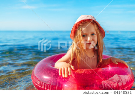 Happy little girl bathing in sea with pink circle 84148581