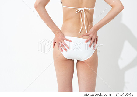 A woman in a bathing suit who is worried about her stomach 84149543